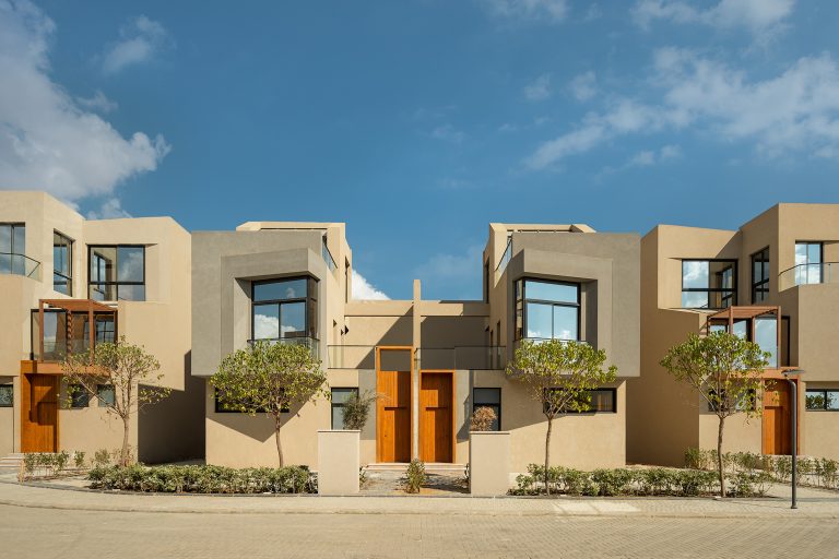 صف من مبانٍ حديثة بواجهات بيج ورمادية ونوافذ كبيرة داخل مشروع Gates Privé
